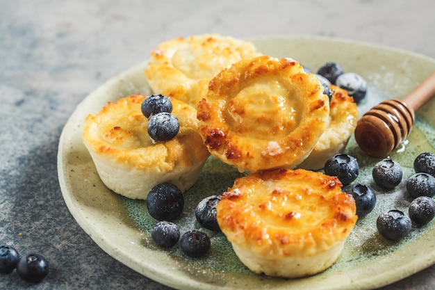 Panquecas de requeijão com mirtilos e mel, fundo cinza. Conceito de cozinha russa.