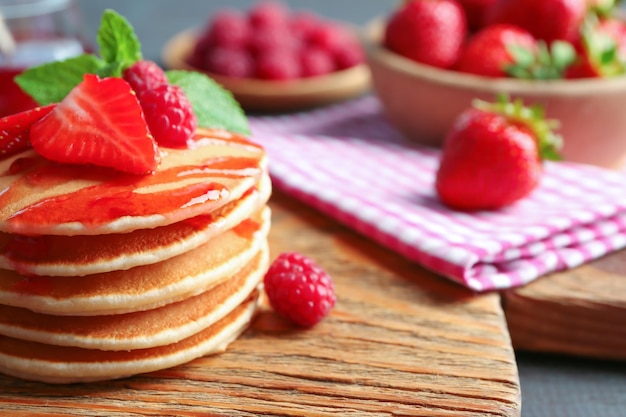 Panquecas deliciosas com framboesa e morango em tábua de madeira