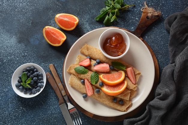 Panquecas doces embrulhadas com menta fresca, morangos, mirtilos, laranjas e geléia