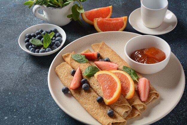 Panquecas doces embrulhadas com menta fresca, morangos, mirtilos, laranjas e geléia