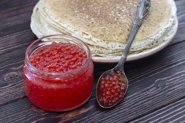 Panquecas em um prato com um pote de caviar vermelho