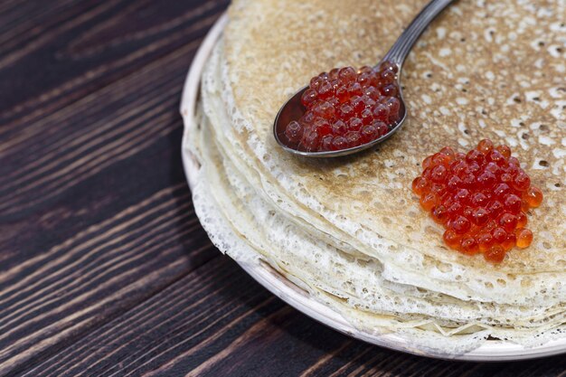 Panquecas em um prato com uma colher e caviar vermelho Semana de panquecas de férias Maslenitsa