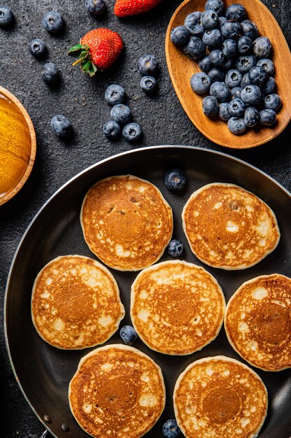 Panquecas em uma frigideira com frutas frescas e mel