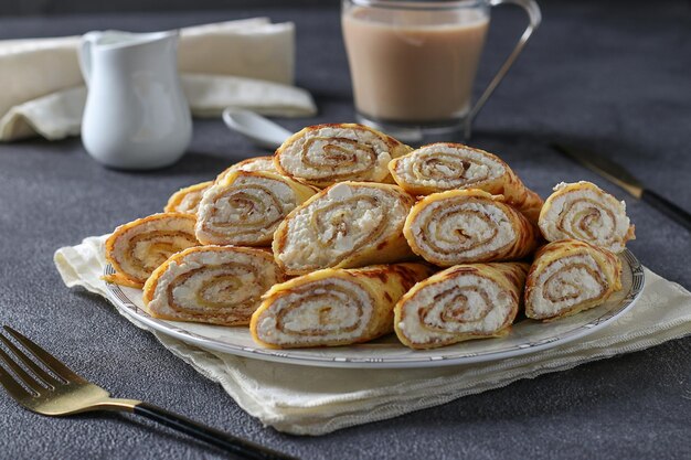 Panquecas finas caseiras com queijo cottage e leite condensado no café da manhã em uma mesa cinza escura