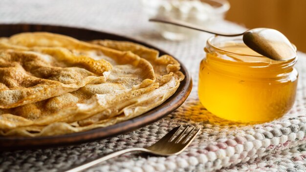 Panquecas finas em um prato, creme de leite e mel