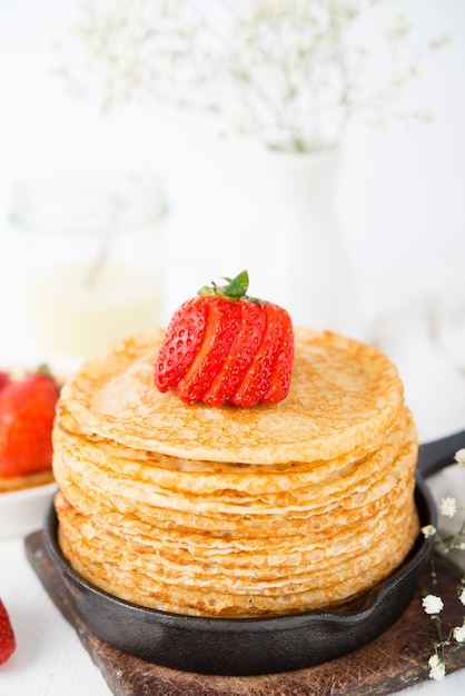 Panquecas finas tradicionais caseiras com frutas vermelhas em uma superfície branca