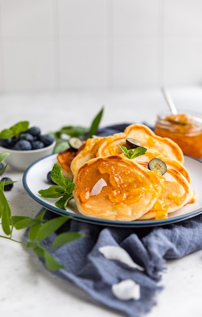 Foto panquecas fofas tradicionais com chips de coco de mirtilos de geléia de laranja e hortelã para café da manhã saudável