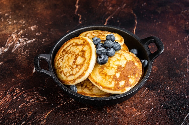 Panquecas fritas com mirtilos frescos e xarope de bordo em uma panela