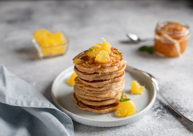 Panquecas integrais com superfície de café da manhã saudável laranja e geléia caseira cinza,