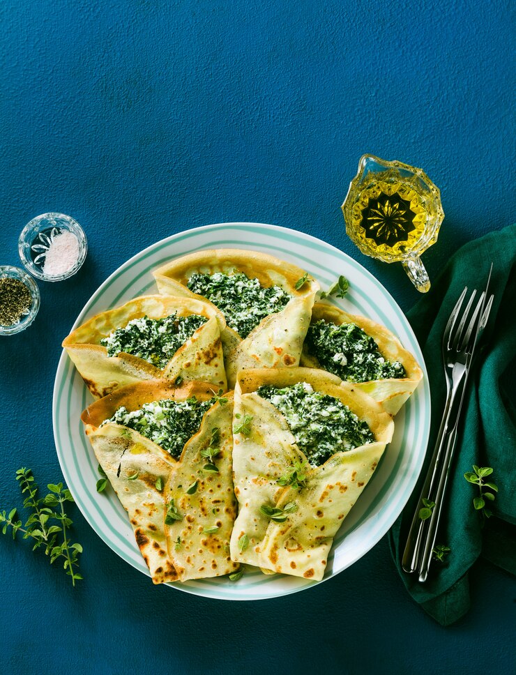 Foto panquecas italianas tradicionais crepes com espinafre e ricota em uma mesa azul servida. dieta vegetariana saudável