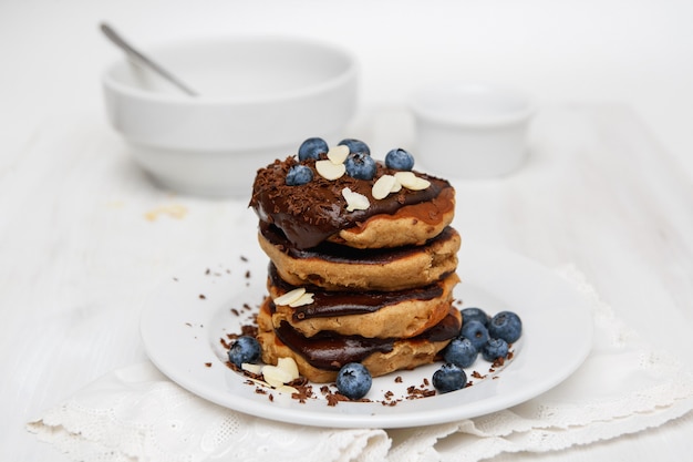 Panquecas no café da manhã com mirtilos e calda de chocolate no prato branco