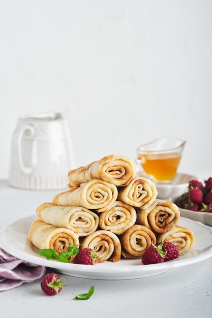 Panquecas Pilha de crepes ou panquecas finas com frutas com framboesas e mel no café da manhã Café da manhã caseiro Espaço para cópia Foco seletivo