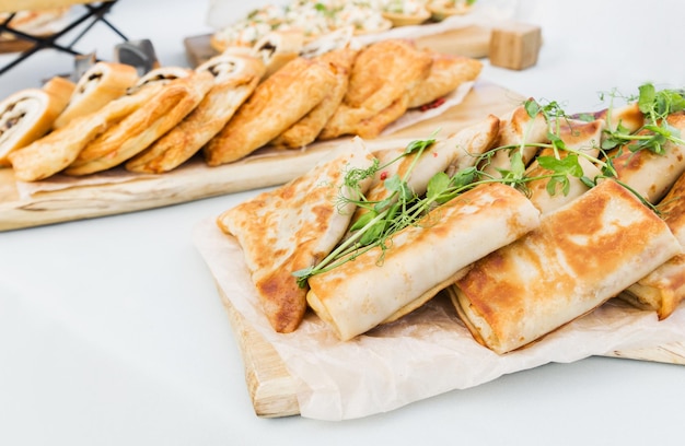 Panquecas recheadas com presunto e queijo, frango e legumes em uma mesa de banquete Foto horizontal