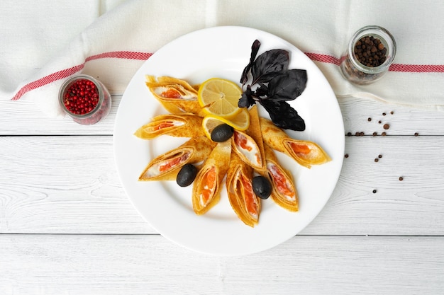 Panquecas russas recheadas com salmão salgado no fundo da mesa de madeira branca