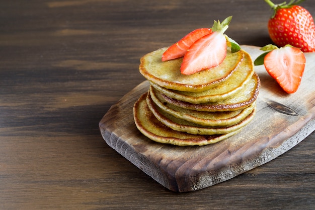 Panquecas vegetarianas com morangos maduros. em uma mesa de madeira.