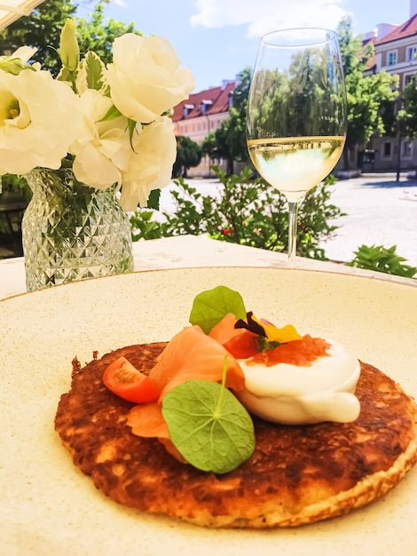 Panqueque de buñuelo de patata con salmón de caviar rojo y crema agria en un restaurante de lujo al aire libre en verano