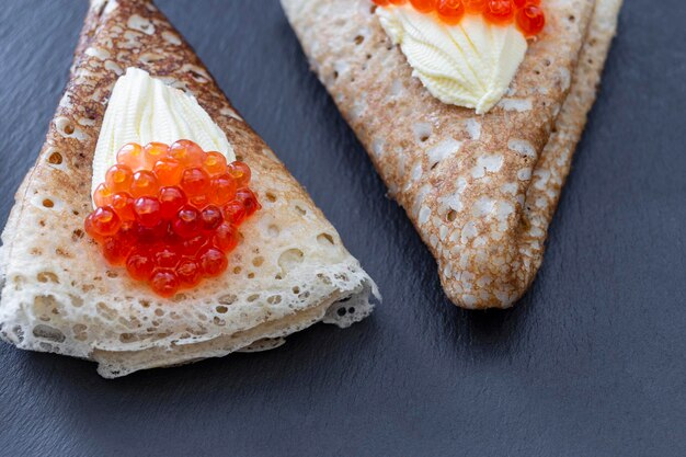 Panqueque con caviar rojo y mantequilla sobre un fondo oscuro Maslenitsa semana de panqueques festivos