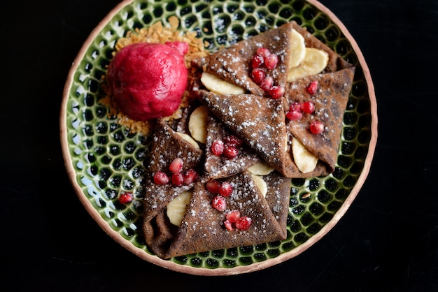 Panqueque de chocolate con plátanos, granada y sorbete