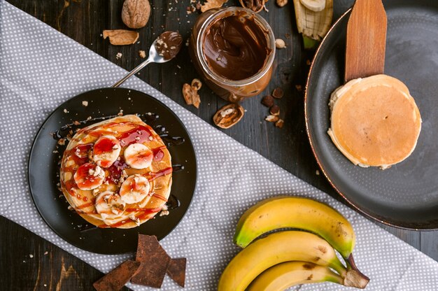 Panqueque con pasta de chocolate y nueces, nueces y plátano sobre una placa negra