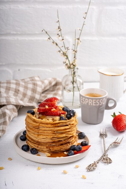 Panqueques con almíbar y bayas en una mesa de desayuno