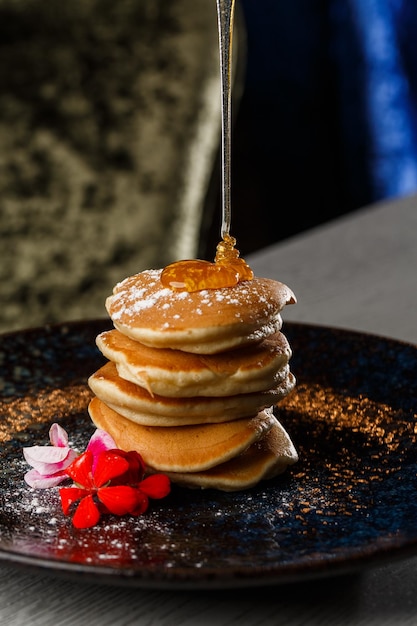 Panqueques americanos con bayas y jarabe de arce en un plato negro aislado en un menú de café de fondo oscuro