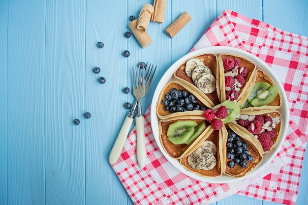 Panqueques americanos clásicos con bayas frescas en una mesa de madera azul. Panqueques con frutas.