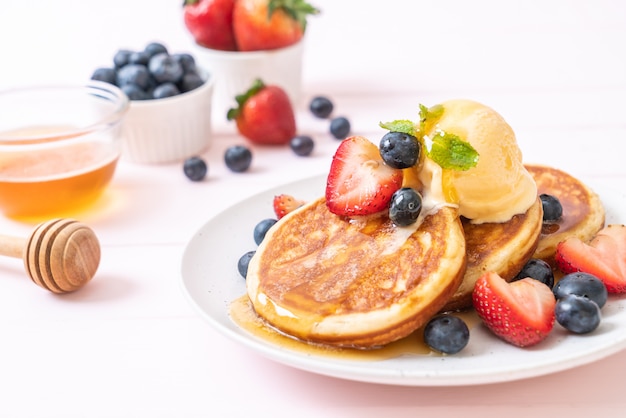 Panqueques con arándanos, fresas, miel y helado de vainilla.