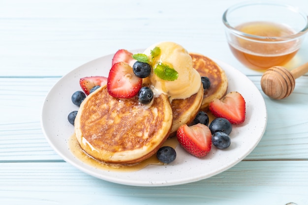 Panqueques con arándanos, fresas, miel y helado de vainilla.