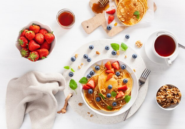 Panqueques con arándanos, fresas, miel y nueces para el desayuno