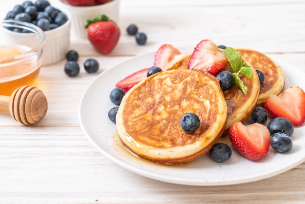 Panqueques con arándanos frescos, fresas frescas y miel.