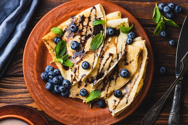 Foto panqueques con arándanos, salsa de chocolate y menta