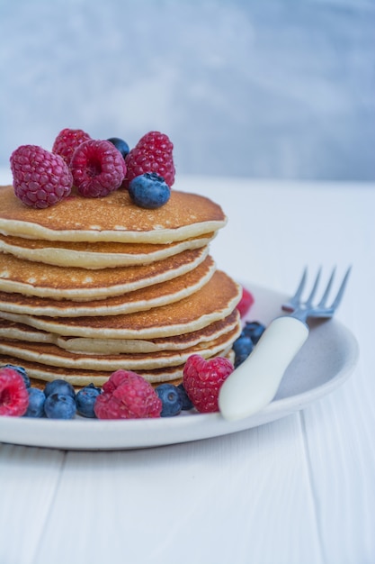 Panqueques con bayas frescas en un azul de madera. Panqueques con frutas. Desayuno casero de verano.