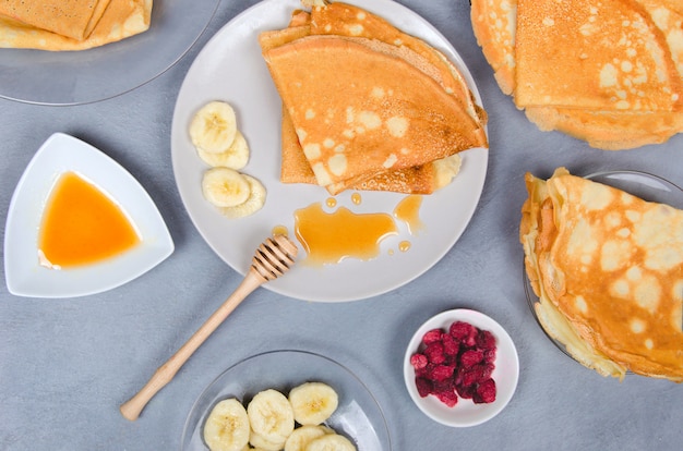 Panqueques con bayas y miel para el desayuno en la mesa gris