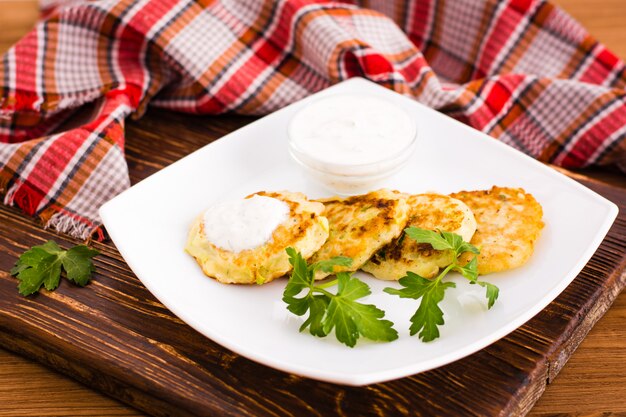 Panqueques de calabacín con salsa y hierba en mesa de madera