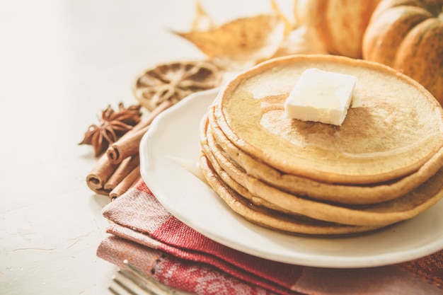 Panqueques de calabaza en un plato blanco con mantequilla y miel