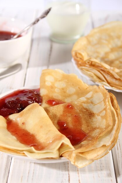 Panqueques calientes finos con mermelada de fresa en una mesa de madera blanca Holiday Maslenitsa