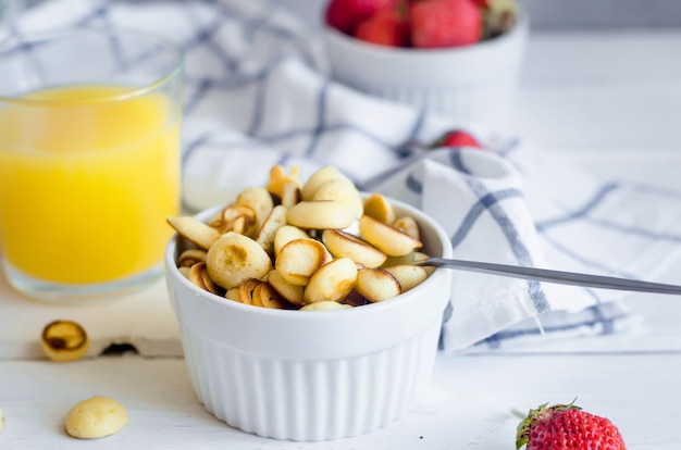 Panqueques de cereales con fresas y vaso de jugo de naranja