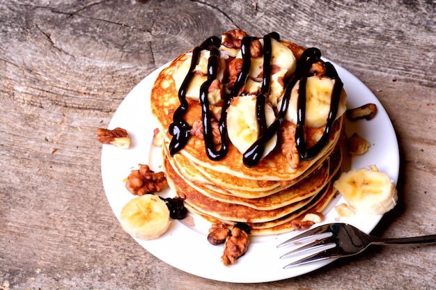 Panqueques con chocolate de nuez de plátano sobre fondo de madera