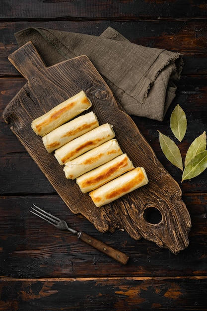 Panqueques cocidos con crepes agrios de relleno salado en la vista superior del fondo de la mesa de madera oscura vieja plana con espacio de copia para texto