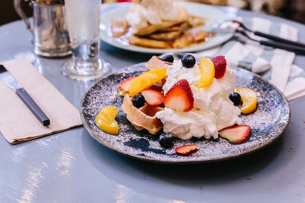 Panqueques con crema de fresa, naranja, arándanos y látigo