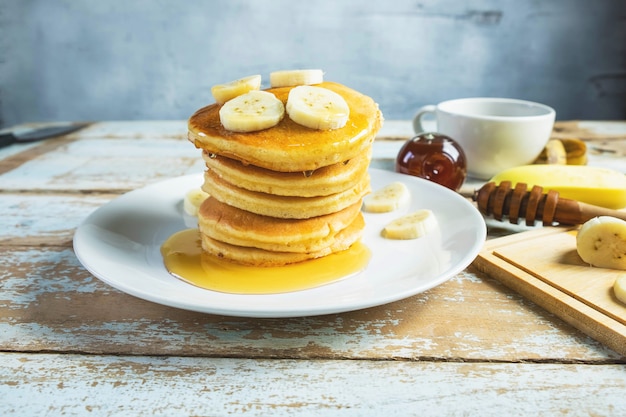 Panqueques cubiertos con miel y plátanos en la mesa