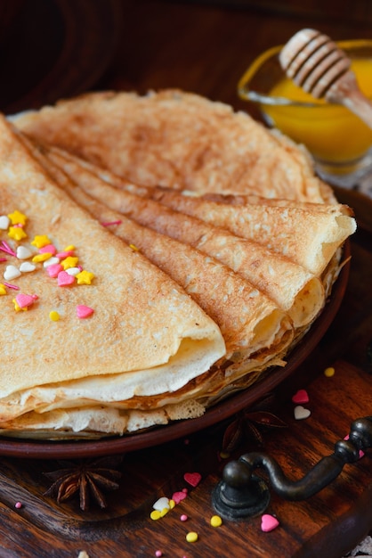 Panqueques dorados con frutas congeladas, decoración y miel en estilo rústico