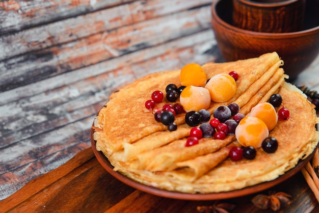 Panqueques dorados con frutas congeladas, decoración y miel en estilo rústico