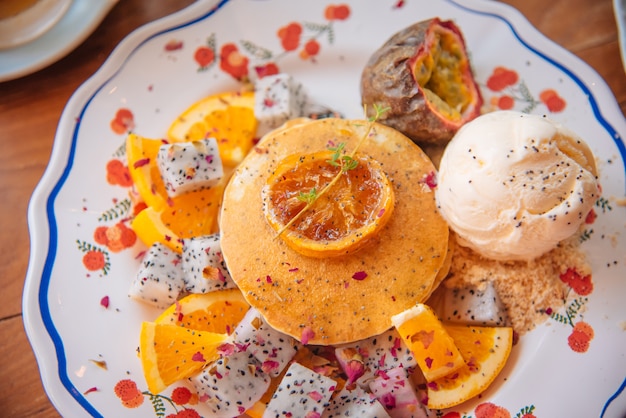 Panqueques dulces con miel y helado de vainilla Frutas con enfoque naranja en panqueque