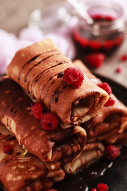 Panqueques dulces con relleno de requesón, servidos con cobertura de chocolate y frambuesas