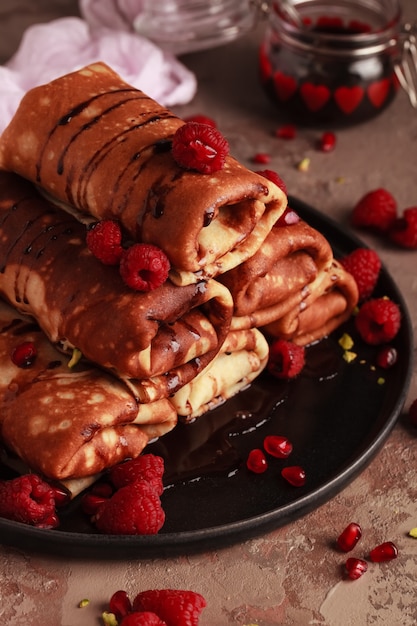 Panqueques dulces con relleno de requesón, servidos con cobertura de chocolate y frambuesas