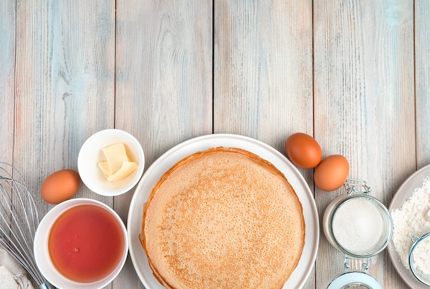 Panqueques e ingredientes para cocinar sobre un fondo de madera clara. Vista superior, con espacio para copiar. Concepto de antecedentes culinarios, Maslenitsa.