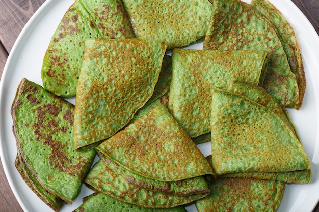 Foto panqueques con espinacas en plato blanco. fondo de desayuno