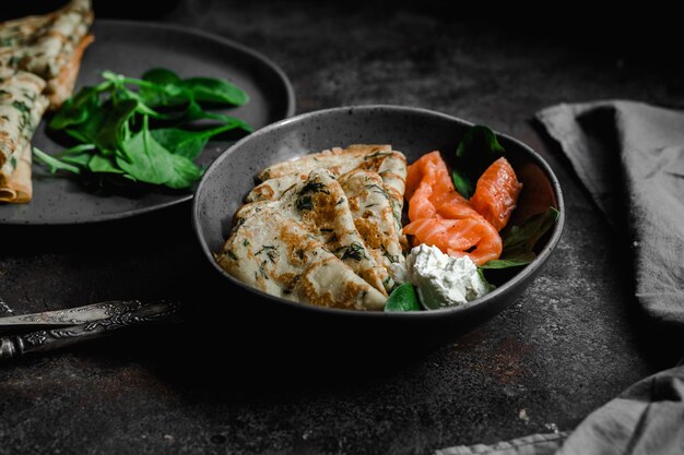 Panqueques finos con hierbas, salmón y queso crema en un plato