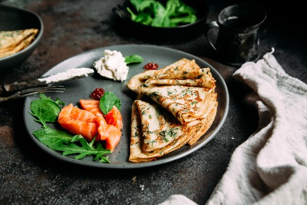 Panqueques finos con hierbas, salmón y queso crema en un plato